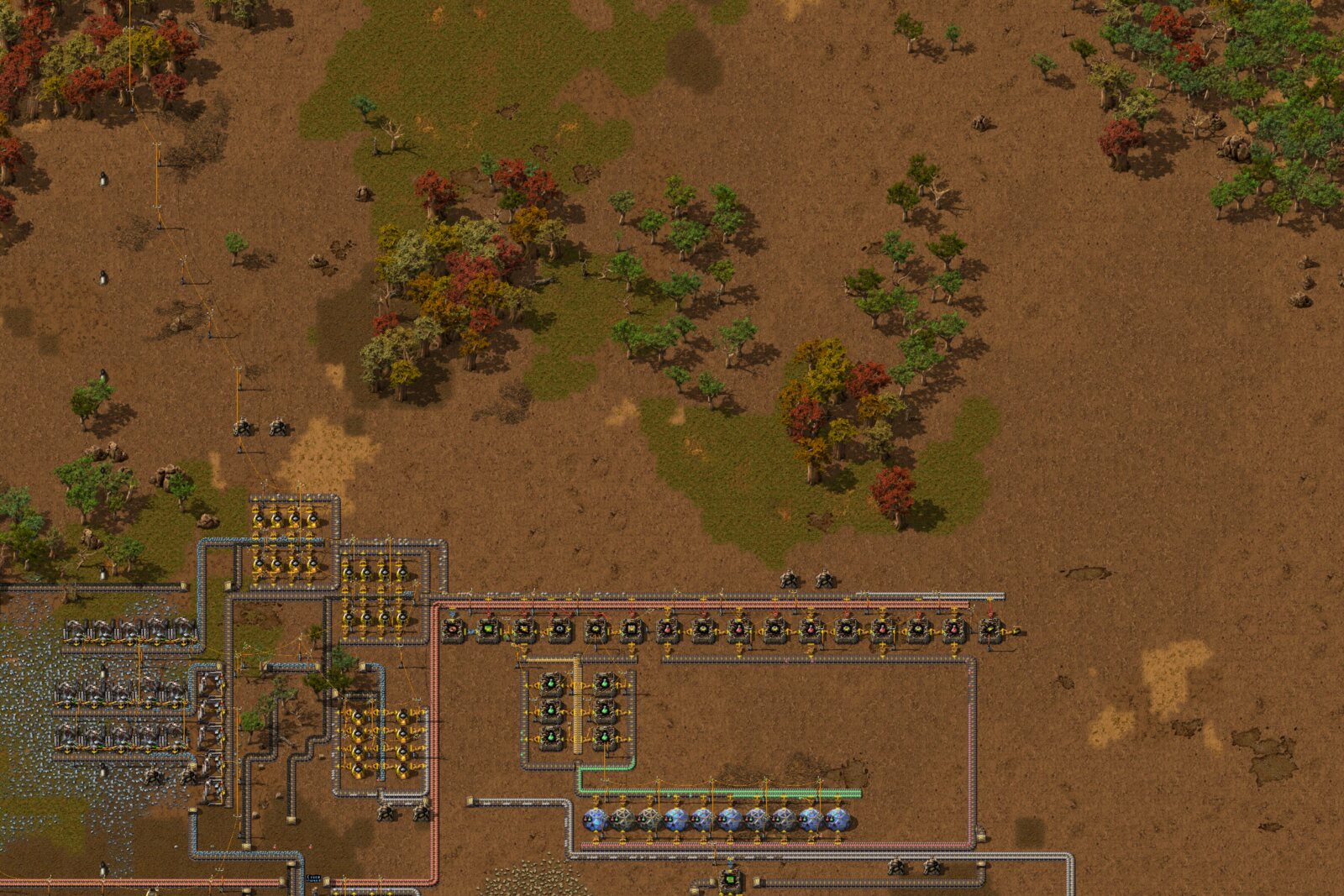 Overhead view of the north half of the base: a long row of furnaces, a block of green-circuit assemblers, and a row of ten labs along the bottom, with autumn-colored trees and grass above.